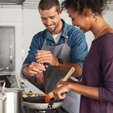 Junges Paar kocht schonend das Gemüse, um die B-Vitamine zu erhalten.