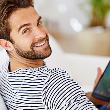 Junger Mann mit Tablet auf dem Sofa