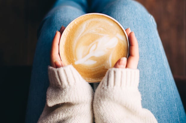 Frau hält Milchkaffee auf dem Schoss